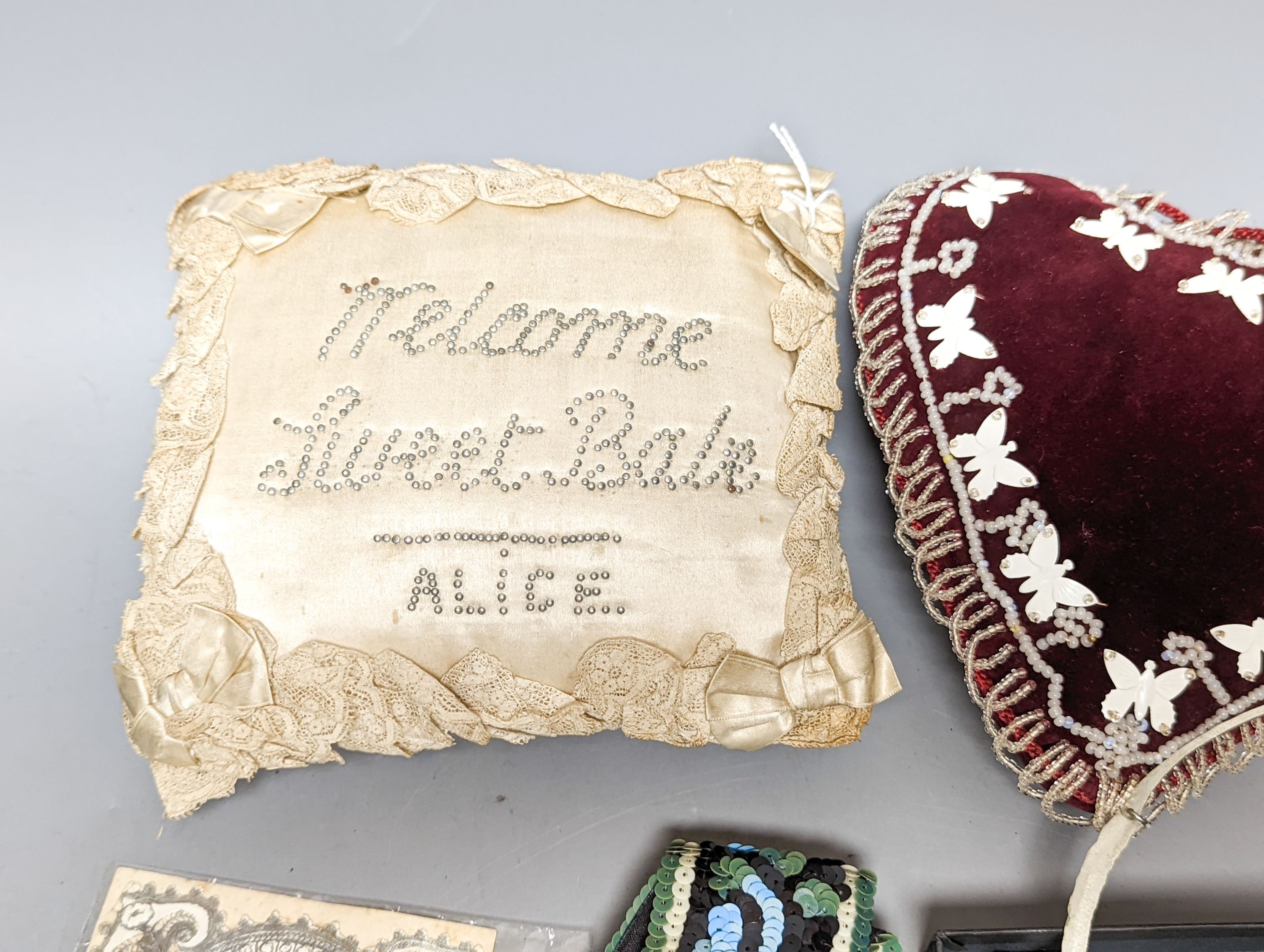 A cream silk pin baby cushion, a valentine cushion, a miser's purse, appliques and sequin collar